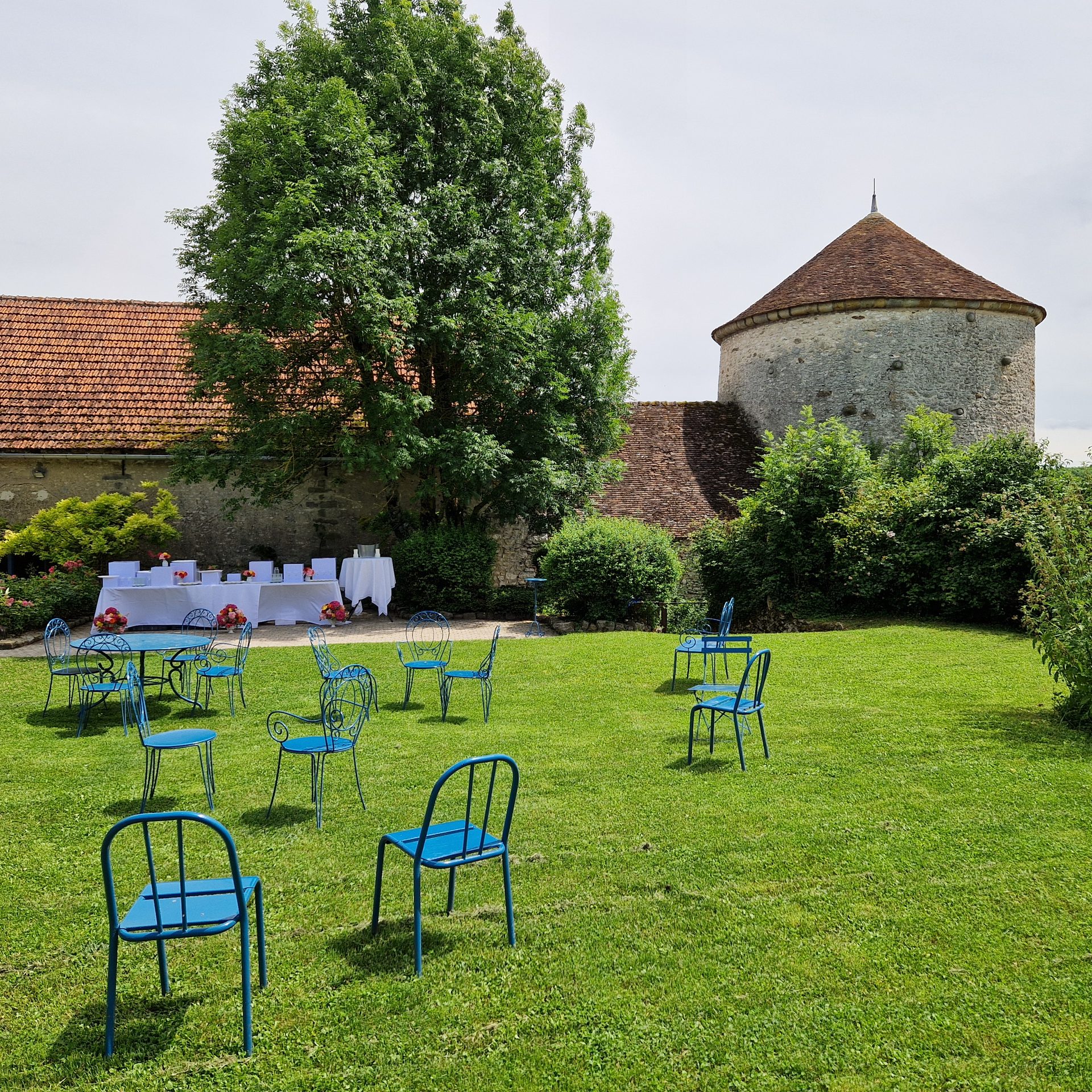 Coin lounge dans le jardin avec chaises bleues, vue sur le pigeonnier