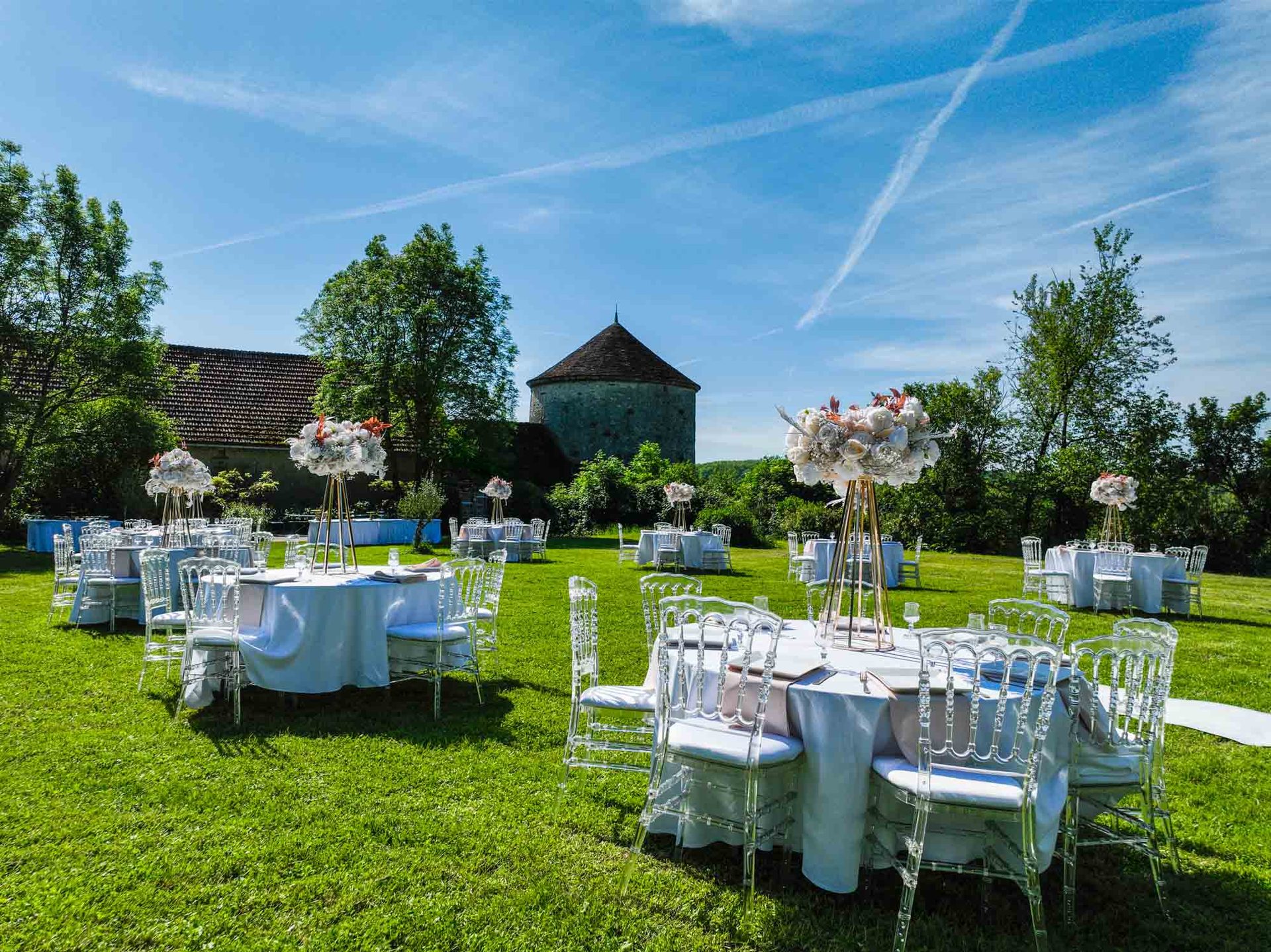 Tables dressées dans le jardin avec compositions florales et allée de cérémonie