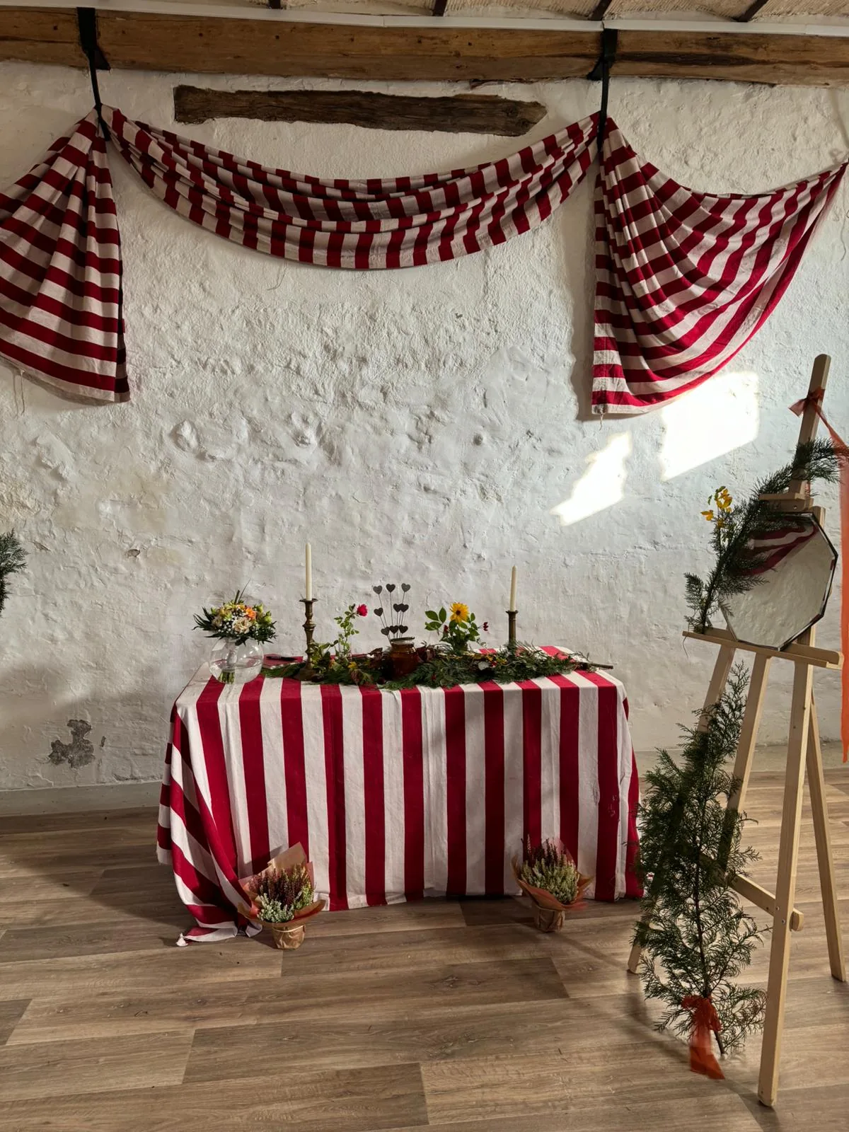 Autel de cérémonie — table décorée de fleurs et bougies, drapés rayés rouges et blancs sur pierre