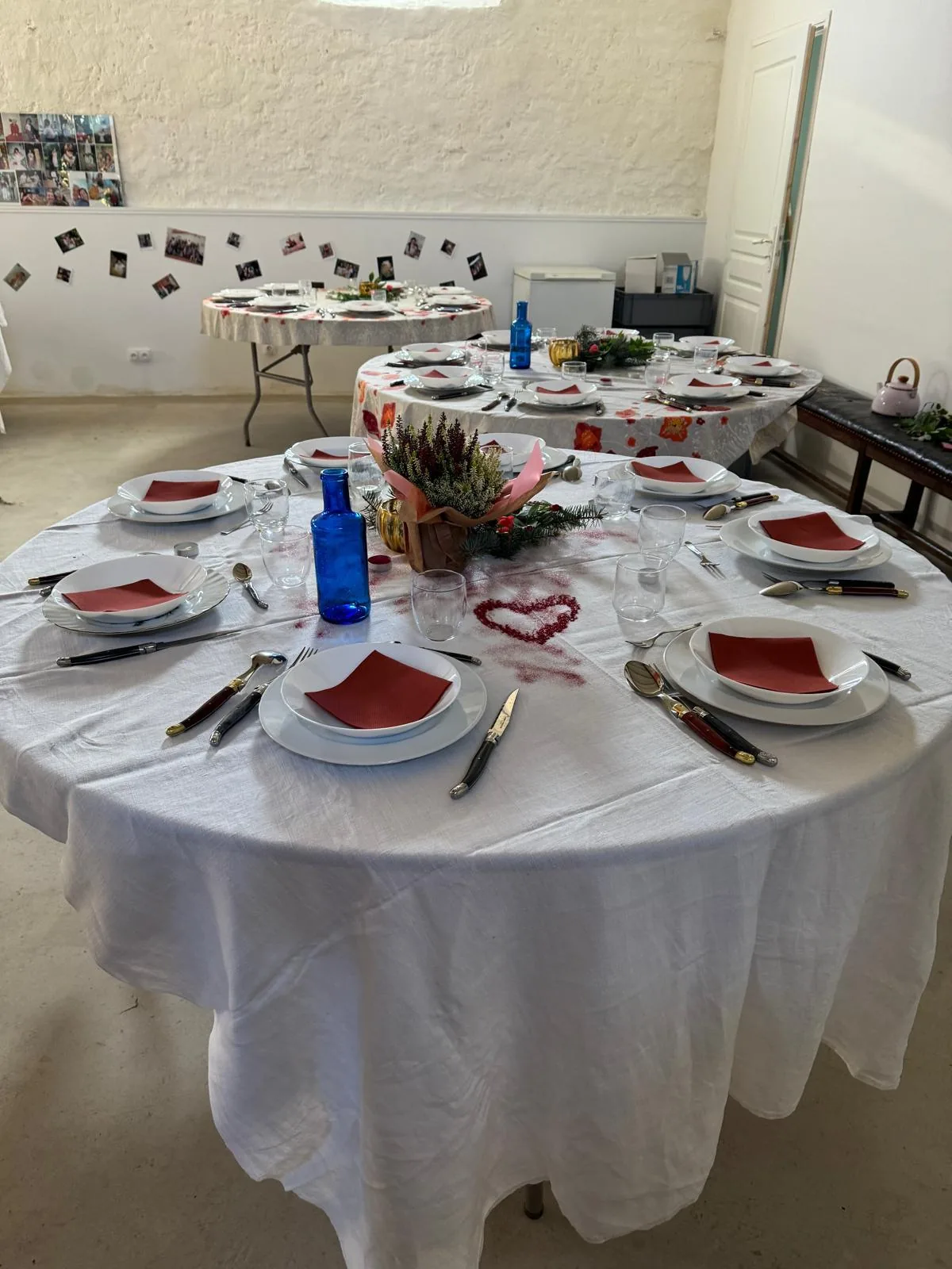 Petite salle en configuration banquet — tables rondes dressées avec serviettes rouges et décoration florale